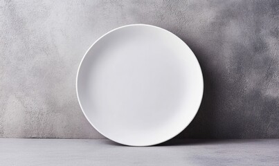 A pristine white plate sits elegantly against a textured gray backdrop, awaiting culinary artistry.