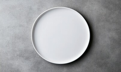 Overhead shot of a pristine white plate resting on a textured gray surface, a study in minimalism.