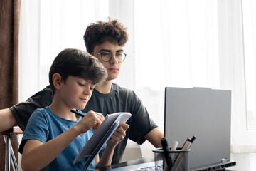 Two brothers focused on a laptop screen, deep in thought and learning. Online learning. Distance...
