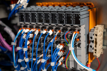 Close-up shot of an electric control panel with various wires and modules mounted on a DIN rail....