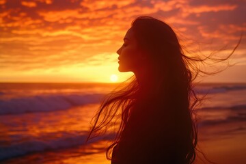 A woman with flowing hair on the beach during golden hour with vibrant sky and ocean waves.