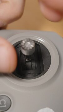 Vertical video. Person Screwing Metal Stick into Joystick Slot of FPV Drone Controller with Fingers in Close-Up View, Macro Perspective, Assembly Concept