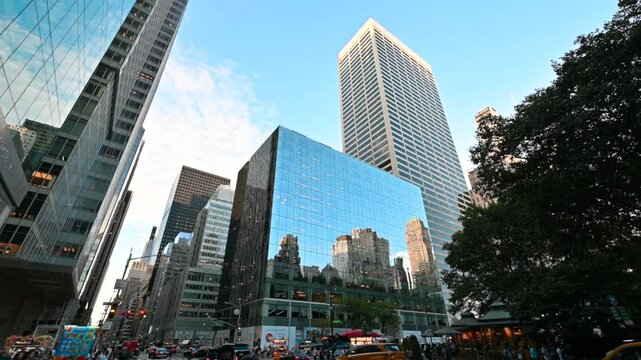 New York City, USA, August 19, 2024. An iconic image of the city: skyscrapers with mirrored facades create beautiful plays of reflections. Traffic on the street and people on the sidewalk. City life.