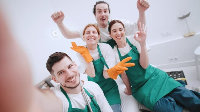 POV Clean and happy team members celebrate after a successful cleaning activity in a bright and modern room while taking a selfie together