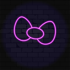 Neon outline of a bow on a brick wall background.