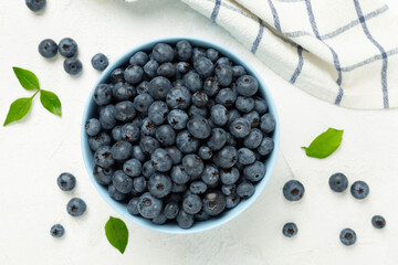 Bowl with fresh bright blueberries on concrete background,top view