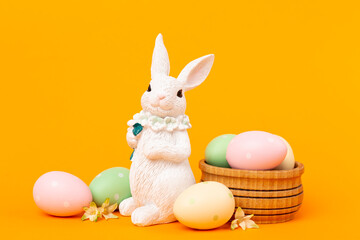 Easter bunny with painted eggs on color background