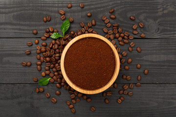 Roasted coffee beans with leaves on wooden background,top view