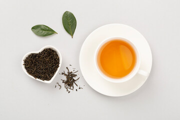 Cup of tea with dry and fresh leaves on color background, top view