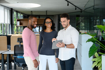 Professional Colleagues Collaborate Over Tablet Discussion In Bright Contemporary Workspace With...