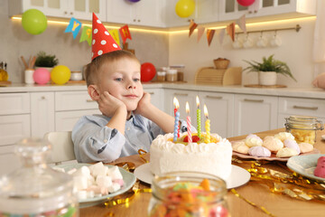 Fototapeta premium Cute little boy with birthday cake at table indoors. Surprise party