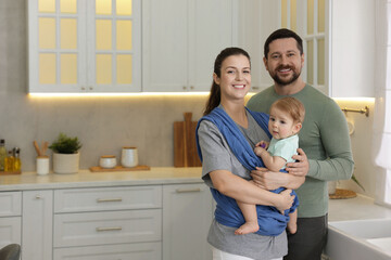 Portrait of happy family indoors, space for text. Mother holding her child in sling (baby carrier)...