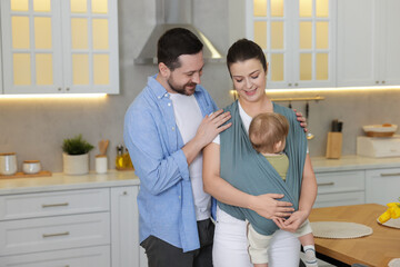 Portrait of happy family indoors, space for text. Mother holding her child in sling (baby carrier)...