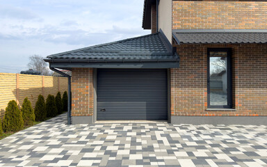 Brick facade of a house with a garage door and a paved driveway