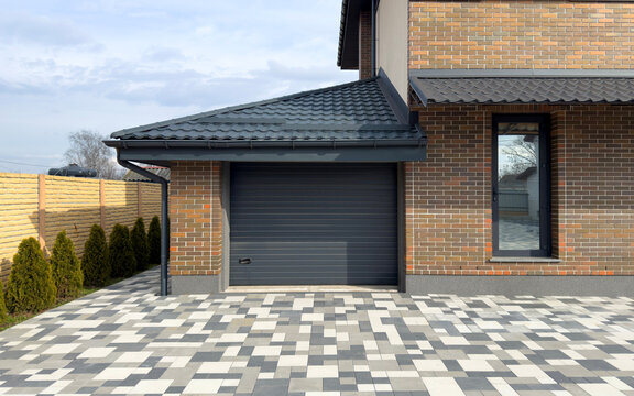 Brick facade of a house with a garage door and a paved driveway