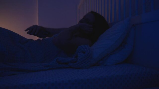 Woman Turns to Side in Bed and Puts Down Smartphone While Falling Asleep After Watching Screen, Side View, Bedtime Routine Concept