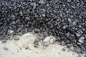 Freshly dumped asphalt on road surface
Black asphalt material spread over a pale roadbed, showing a...