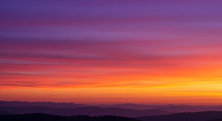Obraz premium Vibrant sunrise painting the sky in purple orange tones above mountain silhouettes
