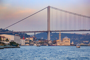 Twilight view of Istanbul, Turkey with the majestic Bosphorus Bridge across the strait and Ortakoy Mosque along the waterfront, golden hour of sunset