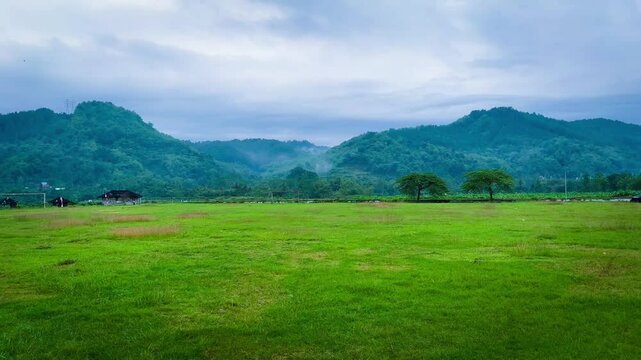 Green Field with Mountain View Under Cloudy Sky