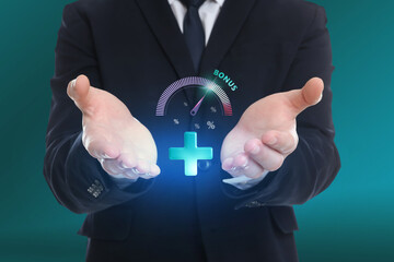 Bonus. Businessman holding virtual plus, percent signs and gauge on teal background, closeup