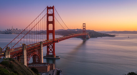 Fototapeta premium Golden Gate Bridge at sunset, a majestic icon silhouetted against a vibrant sky, casting a long shadow across the tranquil waters, showcasing the city skyline in the distance.