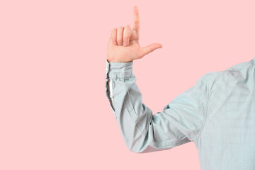 Hand of man showing loser gesture on pink background