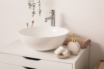 Sink bowl, soap dispenser and bars on chest of drawers in bathroom, closeup
