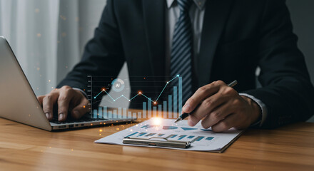A confident businessman analyzing financial data, charting a course to success with a laptop and pen, illuminated by glowing graphs showing upward trends.