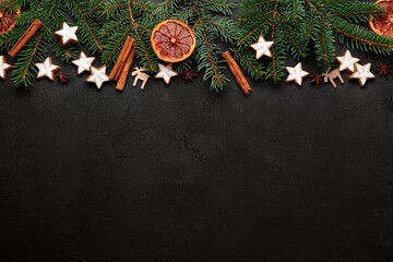 Composition with delicious stars shaped Christmas cookies, spices, orange dried piece and fir tree branches on dark background
