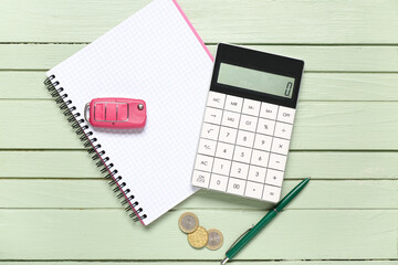 Calculator, car key and notebook on green wooden background. Debt concept. Top view