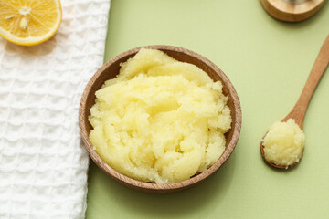 Bowl of natural body scrub and towel on green background