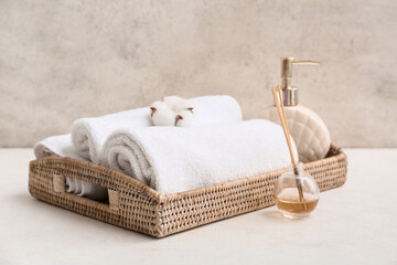 Clean soft towels, bottle of cosmetic product, wicker box and aroma sticks near grunge wall in...