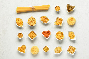 Bowls with different tasty uncooked pasta on light background
