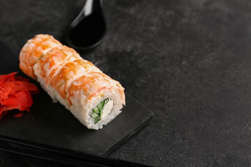 Tasty sushi rolls with chopsticks and marinated ginger on black grunge background, closeup