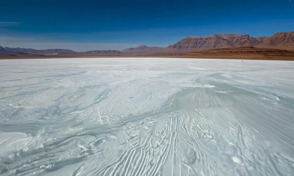 Vast salt flat landscape under a clear blue sky with distant mountains