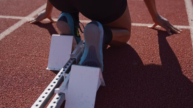 Woman launches off of a starting block during a high school track practice