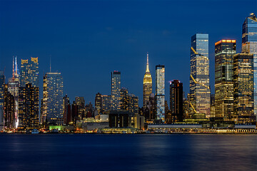 Naklejka premium Stunning night panorama of Midtown Manhattan, New York City, featuring the iconic Empire State Building illuminated among a sea of modern skyscrapers.
