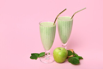 Glasses of fresh spinach smoothie with apple on pink background