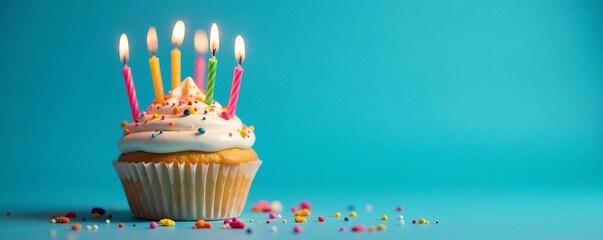 Colorful birthday cupcake with lit candles on blue background, celebration, cupcake