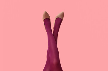 Fototapeta premium Legs of young woman in tights and heeled shoes on pink background
