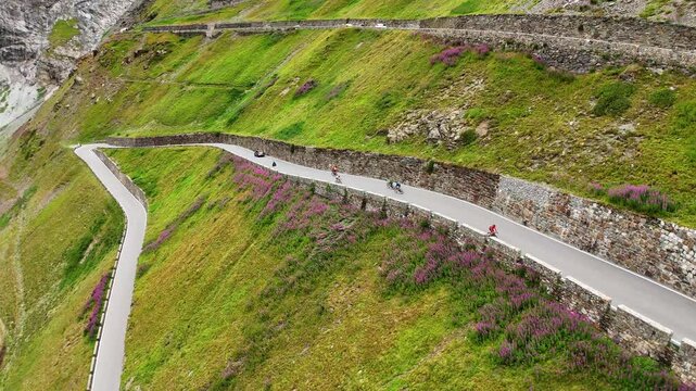 Drone shot of cyclists driving over the hairpin road of the Stelvio Pass, Italy