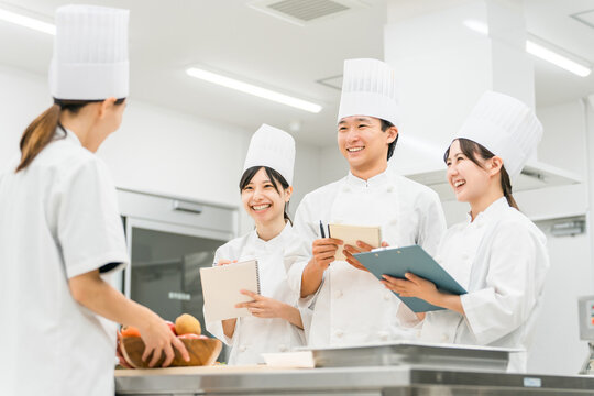 調理師のセミナー・専門学校・社員教育で教える講師の女性と生徒の男女（外食産業）
