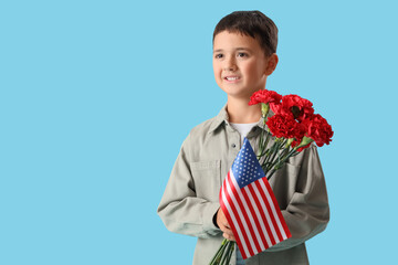 Little boy with carnation flowers and USA flag on blue background. Veterans Day celebration