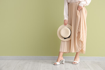 Stylish woman in shoes with hat near green wall