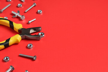 Tap bolts, chrome nuts and pliers on red background