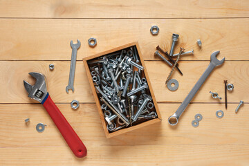 Wrenches and box with tap bolts on wooden background