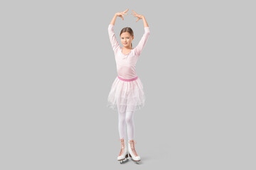 Beautiful young figure skater in ice skates dancing on grey background