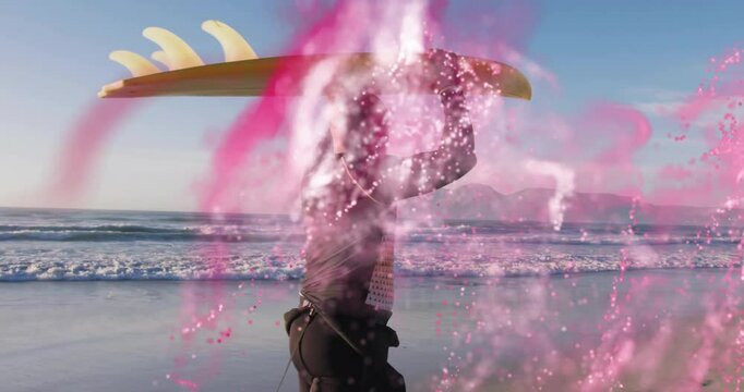 Surfer carrying board on beach with pink abstract animation overlay