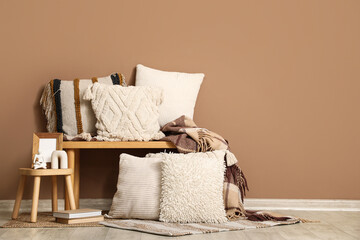 Bench with pillows and decor near brown wall in room